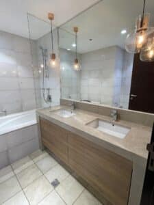 Modern bathroom with double sink vanity, large mirror, marble countertops, and bathtub. Two hanging light fixtures above the countertop add a stylish touch to the design and build of this interior fit-out.