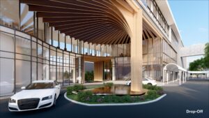 Modern building drop-off area with curved wooden canopy and reflective glass panels. Circular driveway includes a water feature surrounded by landscaped greenery. Several cars are parked nearby.