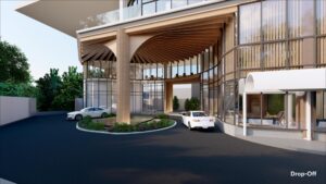 Circular driveway with modern wooden canopy structure at the entrance of a glass building. A white car is parked while another approaches the entrance. Trees are in the background.