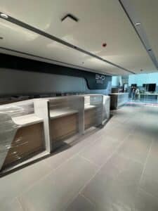 A modern service counter area with partially unwrapped furniture, tiled flooring, and a sign that reads "BYD Service" on the back wall. Two people stand near the entrance.